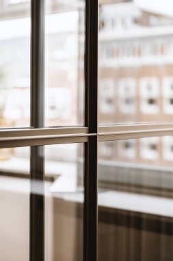 Arka planda binalar ve açık pencerenin yanında bir saat olan bir pencere.