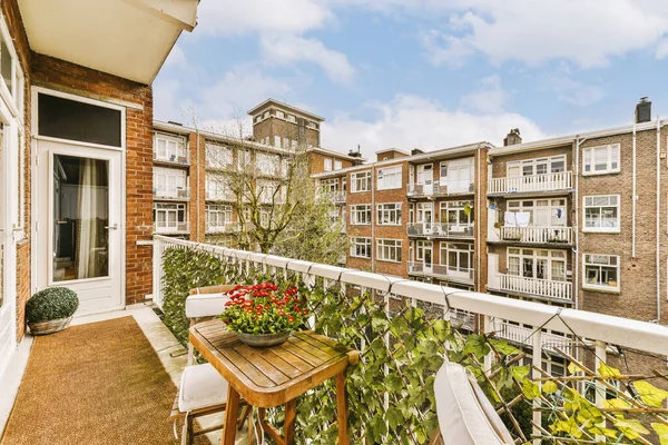 stock image a balcony with flowers on the table and some buildings in the background, taken from an apartments balcony