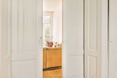 Bir odanın içinde iki beyaz kapı ve kapının önünde kahverengi bir halı.