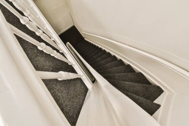 Altında siyah beyaz halı olan bir merdiven, bir apartmanın ikinci katına çıkıyor.