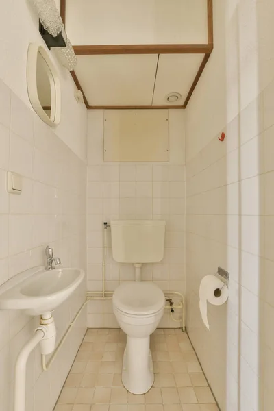 墙上有白色瓷砖的小浴室 上面有天花板 上面有厕所 水池和镜子 — 图库照片