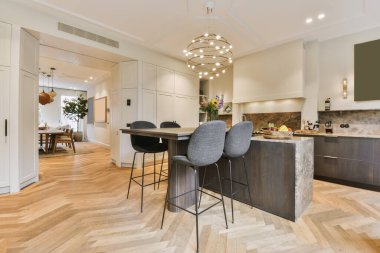 a kitchen and dining area in a house with wood floors, white cabinets, gray bar stools and marble counter tops clipart