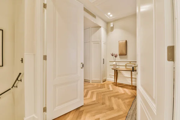 a hallway with hardwood flooring and white trim on the walls, wood floors and an open door leading to another room