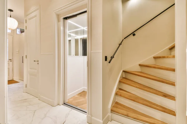 an entry way in a house with marble flooring and wooden steps leading up to the second floor, there is a light fixture