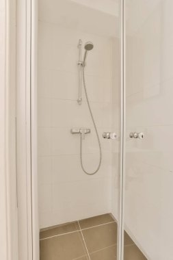 Beyaz fayanslı ve cam duş kapılı bir banyo. Evinizdeki ya da evinizdeki boşluğu nasıl kullanacağınızı gösteriyor.