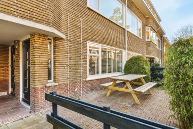 Dışarısı piknik masası ve güneşli, mavi gökyüzü gününde tuğla bir evin önünde bank.