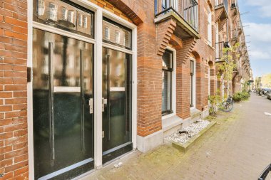 Önünde siyah kapılı ve ortasında iki penceresi olan eski bir tuğla binanın yanına park edilmiş bir bisiklet var.