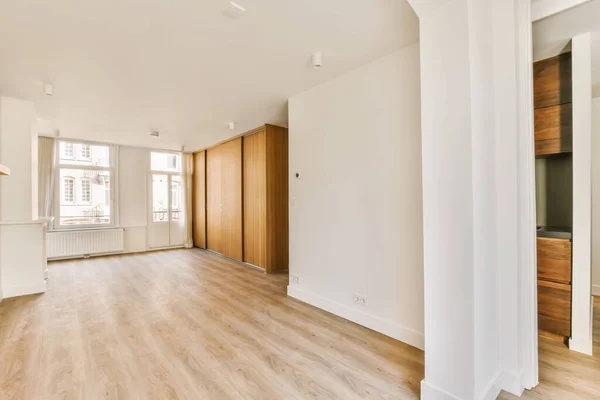 an empty living room with wood flooring and large windows in the room is white walls, hardwood floors and wooden doors