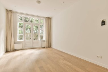an empty room with wooden floors and white walls, there is a large window in the wall to the right