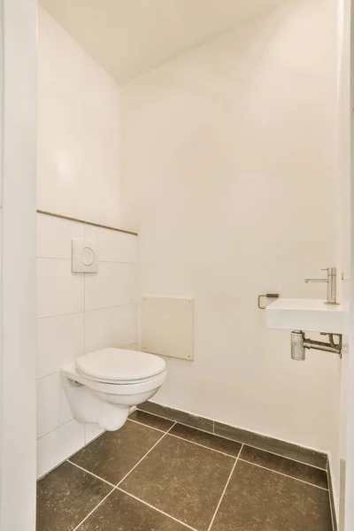隅にタイル張りの床と壁の取り付けられたトイレのある白いバスルーム壁に鏡があります — ストック写真