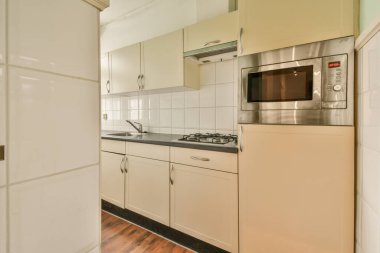 Beyaz dolapları ve siyah tezgahları olan bir mutfak fırının önünde, mikrodalga fırın ve bulaşık makinesinin önünde.