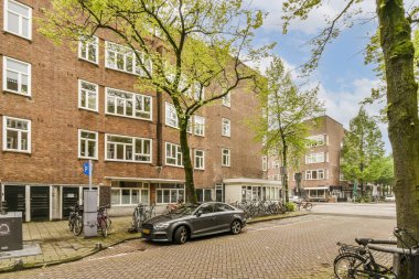 Park etmiş arabaları ve bisikletleri olan bir şehir caddesi. Hollanda, Amsterdam 'da bir apartmanın önündeki kaldırımda.