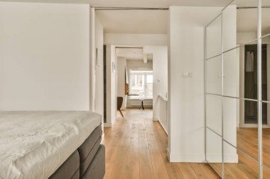a bedroom with white walls and wood flooring the room is well lit by the light coming from the window