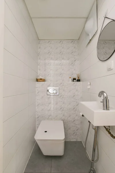 墙角有厕所和水槽的小浴室 墙壁上有白色的瓷砖 还有灰色的混凝土地板 — 图库照片