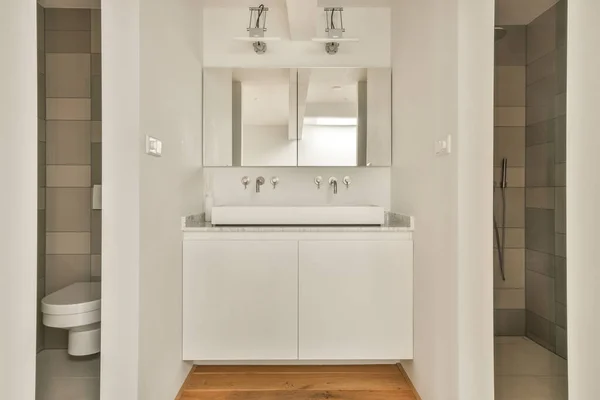 Biała Łazienka Drewnianą Podłogą Lustrami Ścianie Nad Zlewem Wraz Toaletą — Zdjęcie stockowe