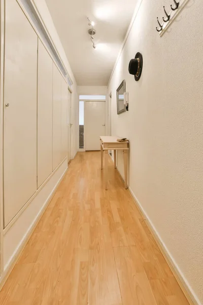 右边有白色墙壁和木制地板的长廊 墙上有一台电视机 — 图库照片