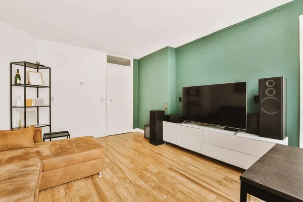 有木制地板和绿色墙壁的客厅 包括安装在墙上的大型平板电视 — 图库照片