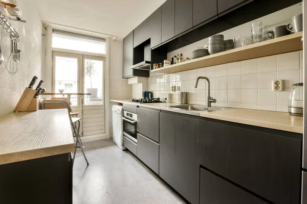 Dapur Dengan Lemari Hitam Dan Ubin Putih Atas Meja Bersama — Stok Foto