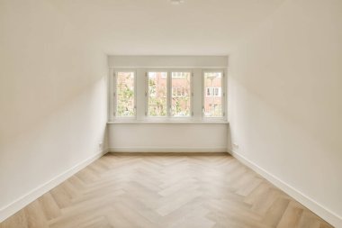 Ahşap zemini ve beyaz duvarları olan boş bir oda. Duvarda sokağa bakan bir pencere var.