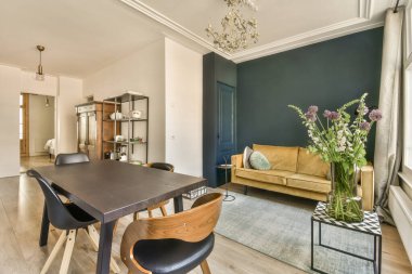 Mavi duvarları ve tavanında beyaz süslemeleri olan bir oturma odası, odasındaki ahşap döşemeler çok temiz.