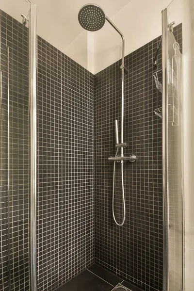 左側にシャワーヘッド付きの黒と白のタイル張りの浴室右側にトイレ — ストック写真