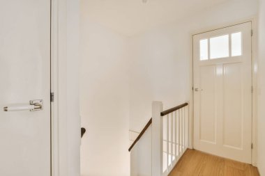 Boş bir evde beyaz duvarları ve ahşap döşemeleri olan bir koridor. Pencereden gelen ışığı gösteriyor.