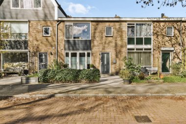 Ön tarafında ağaçlar ve bitkiler olan bir evin dış görüntüsü. Görüntü içeriden, sokağa doğru çekiliyor.