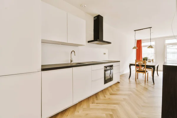 stock image a kitchen with white cabinets and black counter tops on the island in front of the sink is next to the dining table