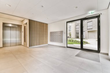 Boş bir ofis, yerde cam kapılar ve beyaz fayanslar var. Odada kimse yok.