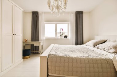 Yatağı olan bir yatak odası ve yatağın önündeki duvarda beyaz bir sandalye var.