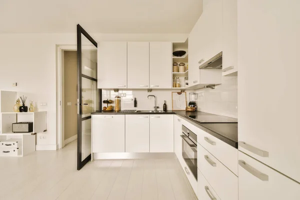 在这个狭小的空间里 岛上有一个现代化的厨房 有白色的橱柜和黑色的台面 — 图库照片