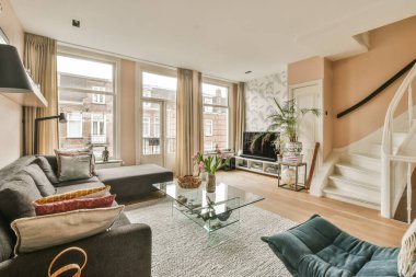 Oturma odası, kanepeler, sehpa ve ikinci kata çıkan bir apartman dairesi.