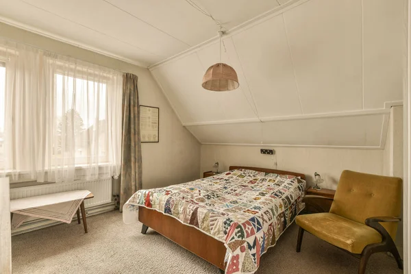 stock image a bedroom with a bed, chair and window in the corner to the left is an image of a city