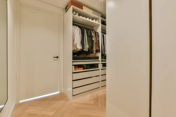 木製の床と白い壁を持つクローゼットの中で ドレッシングルームにつながるオープンドアを含む — ストック写真