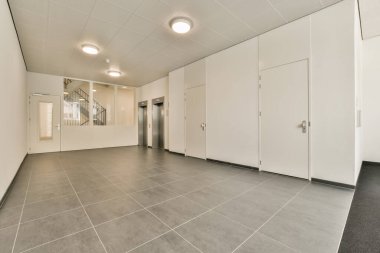 Beyaz duvarları ve gri zemini olan boş bir ofis, sağ tarafında tek bir kapı yok.