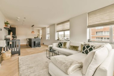 Odasında ahşap döşeme ve beyaz koltuklar olan bir oturma odası, şömine de dahil olmak üzere modern dekorlarla süslenmiştir.