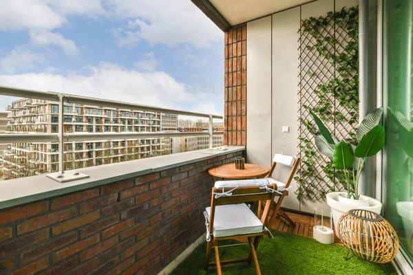 Duvarın önünde yeşile boyanmış birkaç sandalye ve bitki olan bir balkon.
