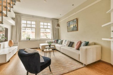 Oturma odası, ahşap döşemeler ve pencerenin önünde beyaz koltuklar, sokağa bakıyor.