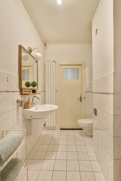墙上有一个有大理石地板和白色瓷砖的浴室 里面有厕所 镜子和毛巾架 — 图库照片