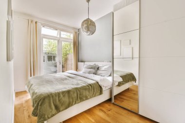 Yatağı, şifoniyeri ve aynası olan bir yatak odası.