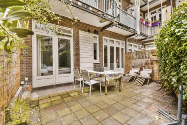 a patio with chairs, table and umbrellas in the sun on a sunny day at an apartment buildings back yard