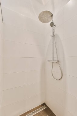 a shower with white tiles on the walls and floor in a modern style bathroom, it is clean and ready for guests to use