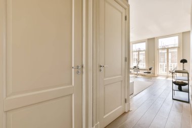 an empty room with wooden floors and white walls, two doors open on the right side there is a small desk in the middle