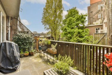 an outside area with some plants and pots on the side of a building, in front of a wooden fence