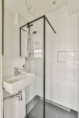 Zeminde siyah beyaz fayanslar, duş kabini ve lavabosu olan modern bir banyo bu resimde görünür.