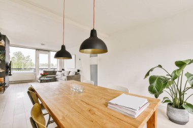 Ahşap masalı bir yemek odası ve tavandan sarkan iki lamba açık bir yaşam alanıdır.