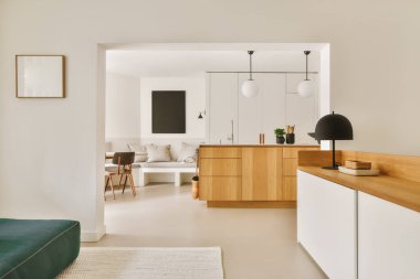 Odanın ortasında beyaz duvarları ve ahşap mobilyaları olan bir oturma odası yeşil bir kanepe.