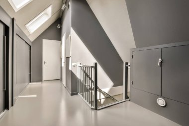 İkinci kata çıkan merdivenleri ve üst kattaki tavan pencereleri olan bir ofis binasında koridor.