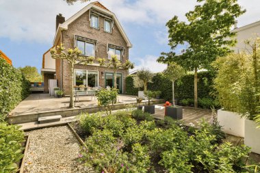 Bahçenin ortasında bir ev. Evin kenarında bir sürü çiçek ve bitki yetişiyor.