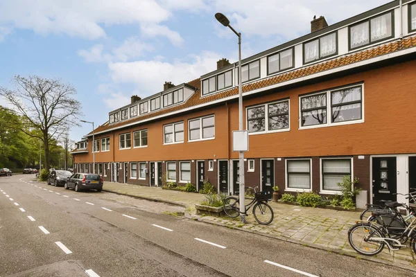 stock image an urban street with parked cars and bicycles on the sidewalk in front of two buildings, one has a bicycle leaning against the wall